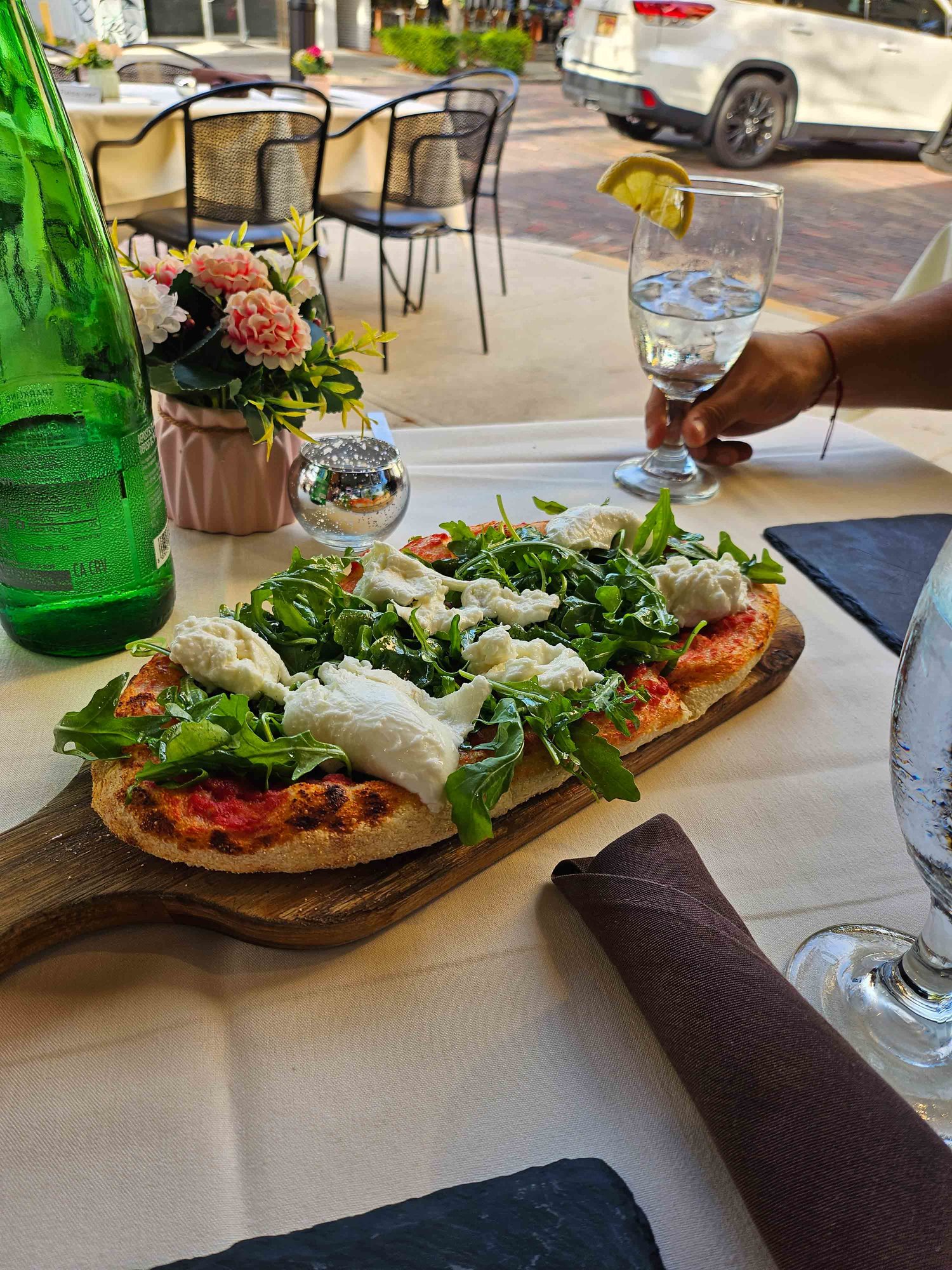 table with white tablecloth and flatbread with leafy greens and cheese